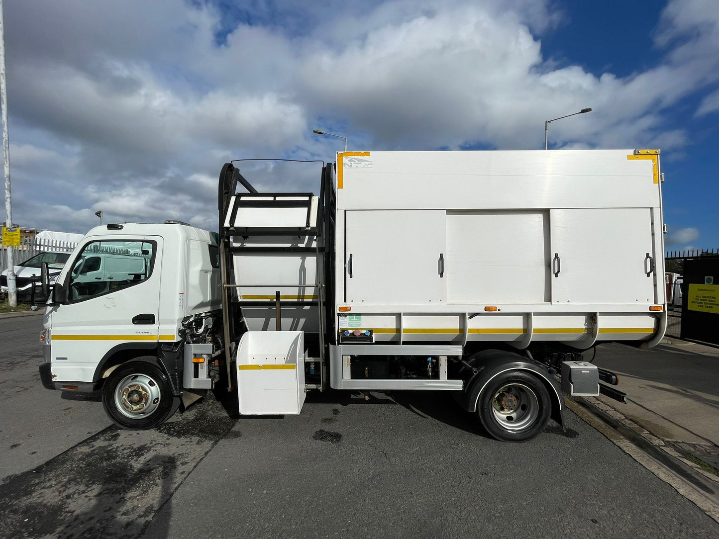 White truck with a cargo bed on a road under a cloudy sky