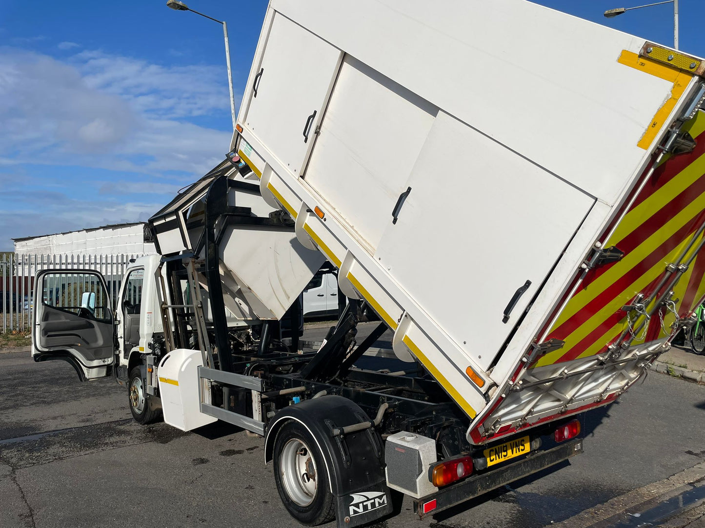 Garbage truck with open rear door on a street