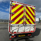 Back of a vehicle with red and yellow hazard stripes on a road.