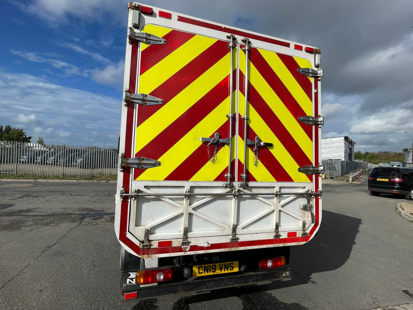Back of a vehicle with red and yellow hazard stripes on a road.