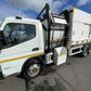 White garbage truck with open rear compartment on a road