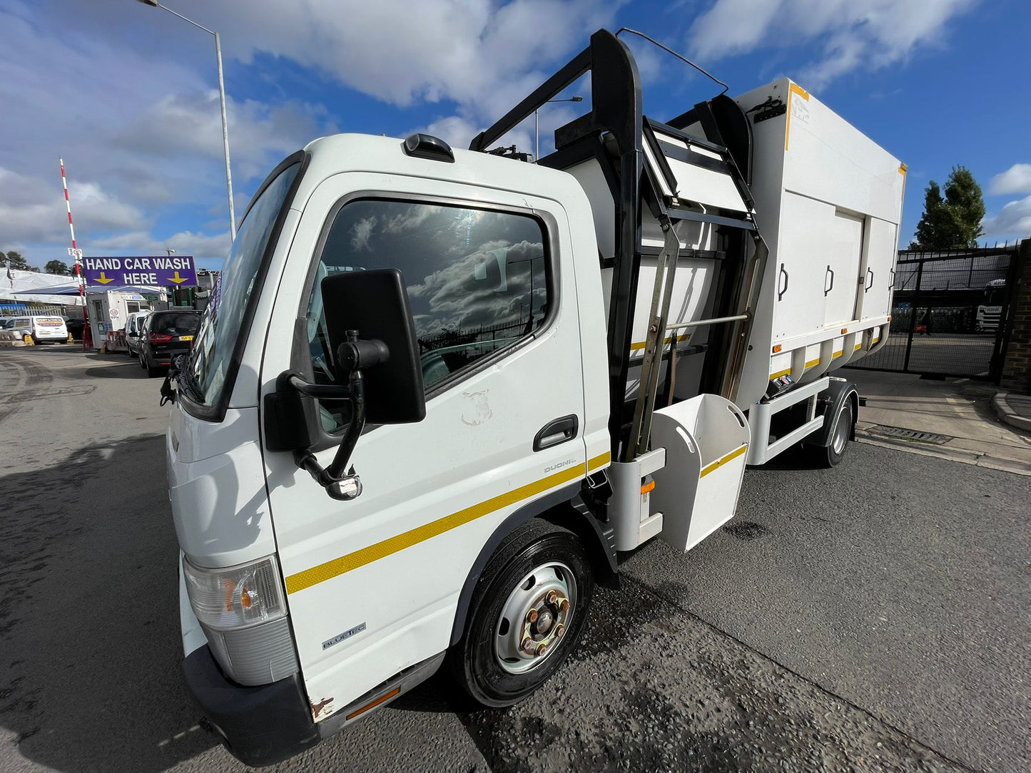 White garbage truck with a yellow stripe on a street